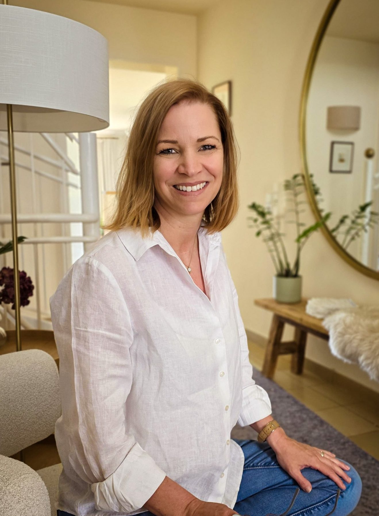 Katrin Pötzsch - Interior Designerin und Wirtschaftsingenieurin Katrin Pötzsch in einem hellen Raum mit Pflanzen und einem großen Spiegel.
