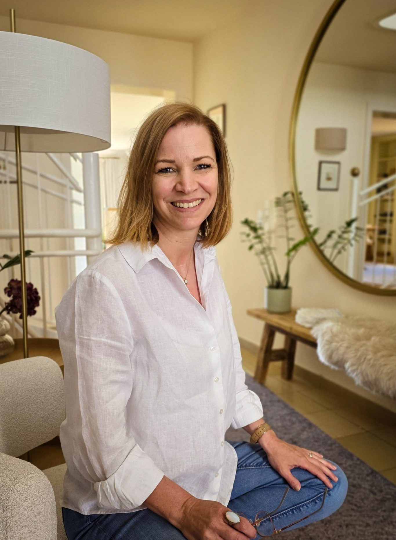Katrin Pötzsch - Interior Designerin und Wirtschaftsingenieurin Katrin Pötzsch in einem hellen Raum mit Pflanzen und einem großen Spiegel.